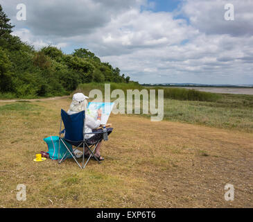 Artist sitzen Malerei die Landschaft in Pagham Harbour, West Sussex, England, Großbritannien Stockfoto