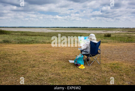 Artist sitzen Malerei die Landschaft in Pagham Harbour, West Sussex, England, Großbritannien Stockfoto