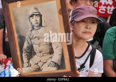 Tomoko Koseki hält ein Foto von ihrem Onkel in WWII Uniform während einer Protestaktion gegen japanische Premierminister Abe Sicherheitsrichtlinien auf Japans Parlament in Tokio am 15. Juli 2015. "Er starb, als er erst 25 Jahre alt, war wir nicht einmal wissen, wo," sagte der 67 Jahre alte Koseki über den Onkel, den sie nie erfüllen konnte. "Das sollte nie wieder passieren." Nach Angaben der Organisatoren, Studenten Emergency Action für die liberale Demokratie (SEALDs), nahmen etwa 100.000 Menschen die Polizei viel Mühe zu kontrollieren. Früher in den Tag hatte ein Sonderausschuss des Unterhauses für eine Rechnung gelöscht. Stockfoto