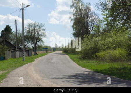 die asphaltierte Straße führt durch das Dorf der Ferne Stockfoto