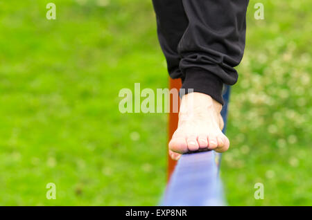 Nahaufnahme von mans Füße Ausgleich ein Seil oder eine Slackline in Park Umgebung Stockfoto