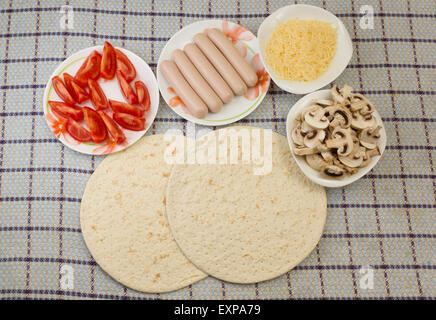 Zutaten für die Zubereitung von Pizza sind auf Platten verteilt und sind gebrauchsfertig Stockfoto