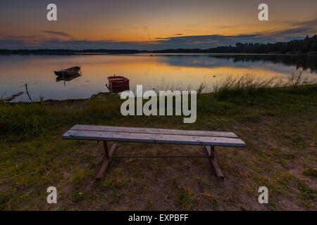 Schöner See Sonnenuntergang mit Fischer Boote und Bank am Ufer. Polnischen See in Masuren. Polnische Seenlandschaft Stockfoto