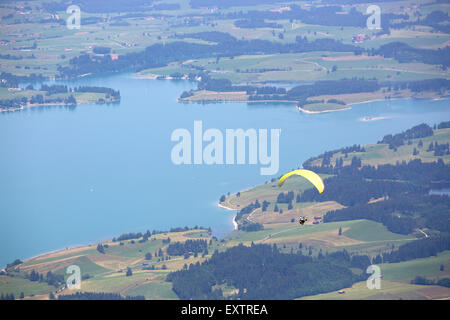 Gleitschirm fliegen über See Forggensee in bayrischen Bergen Stockfoto