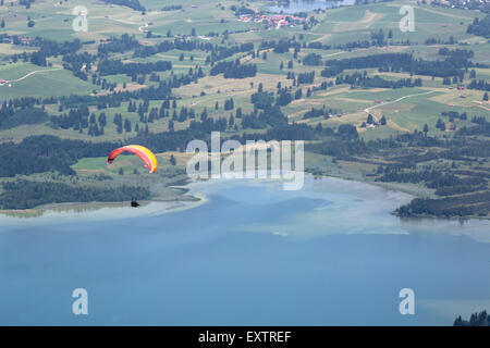 Gleitschirme fliegen über See Forggensee in bayrischen Bergen Stockfoto