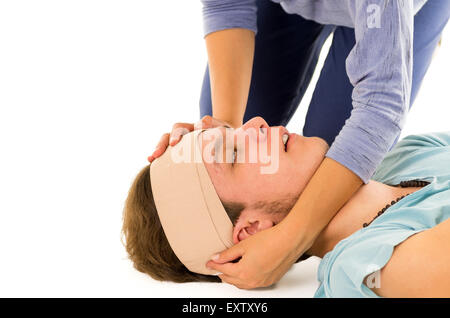 Männerkopf mit Bandage und müde Augen liegen, während weibliche Hände halten Stockfoto