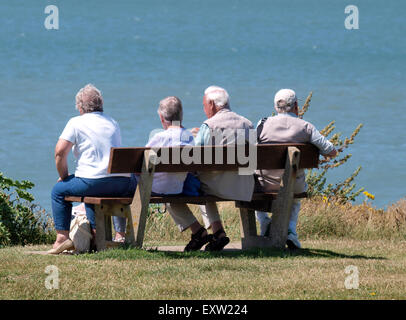 Rentner saß auf einer öffentlichen Bank, Blick auf das Meer, Woolacombe, Devon, UK Stockfoto