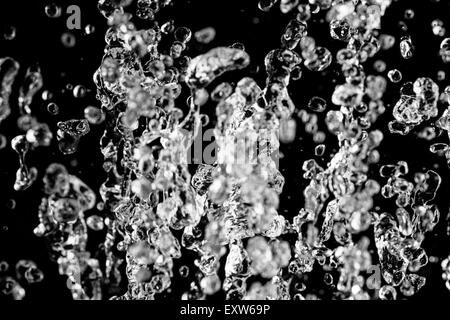 Tropfen Wasser fliegen im Dunkeln Stockfoto