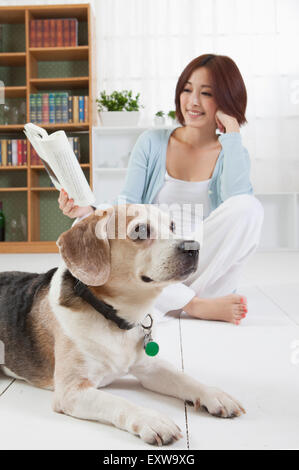 Junge Frau mit ihrem Hund zu sitzen und ein Buch zu lesen, Stockfoto