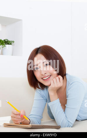 Junge Frau liegend auf Vorderseite und lächelt in die Kamera, Stockfoto
