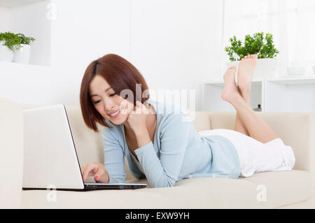 Junge Frau liegend auf Vorder- und mit Laptop, Stockfoto