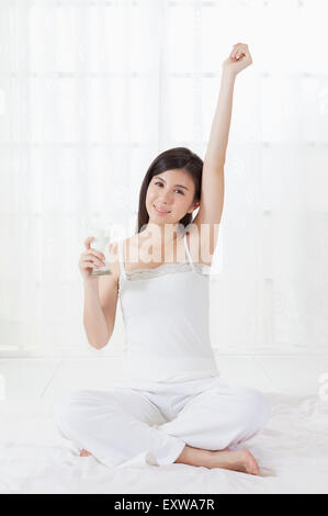 Junge Frau sitzt und hält ein Glas Milch, Stockfoto