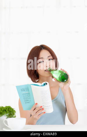 Junge Frau trinken und ein Buch zu lesen, Stockfoto