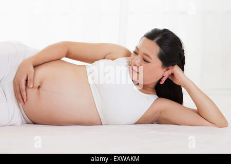 Schwangere Frau auf der Seite liegend und wegsehen, Stockfoto