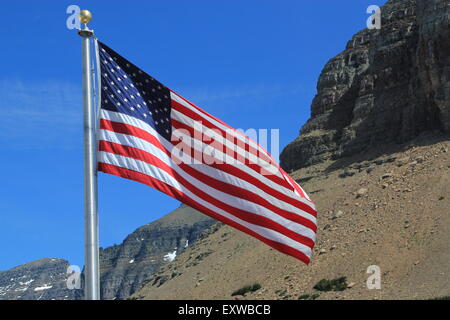 Amerikanische Flagge, zeigt die volle Sterne und Streifen, auf einem silbernen Fahnenmast im Wind gegen einen blauen Himmel und Berge Stockfoto