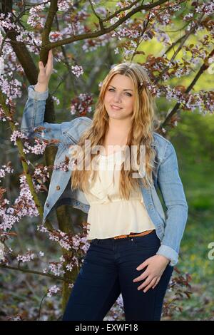 Junge Frau am blühenden Kirsche Baum, Porträt Stockfoto