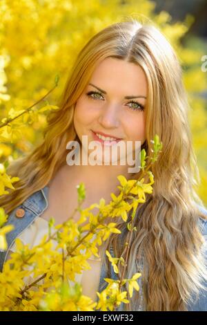 Junge Frau am blühenden Forsythien, Porträt Stockfoto