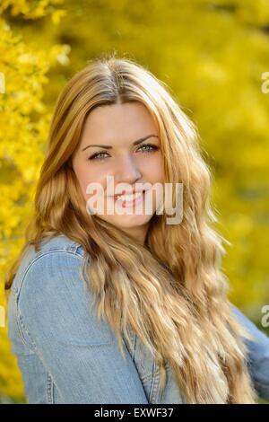 Junge Frau am blühenden Forsythien, Porträt Stockfoto