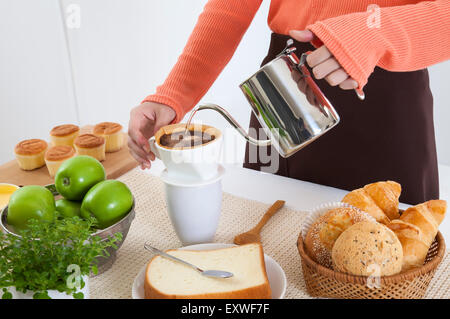 Junge Frau, die Zubereitung von Kaffee in der Küche zum Frühstück, Stockfoto