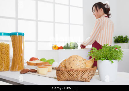 Junge Frau in der Küche Stand und wegschauen mit Lächeln, Stockfoto