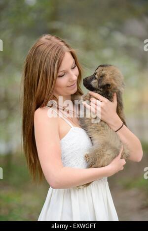 Junge Frau mit einem Mischling Hund Welpen im Garten Stockfoto