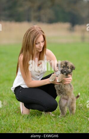 Junge Frau mit einem Mischling Hund Welpen im Garten Stockfoto