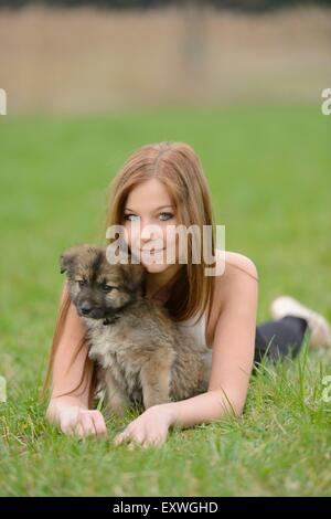 Junge Frau mit einem Mischling Hund Welpen im Garten Stockfoto