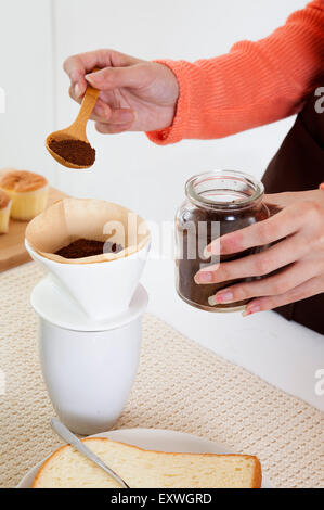 Junge Frau, die Zubereitung von Kaffee in der Küche, Stockfoto