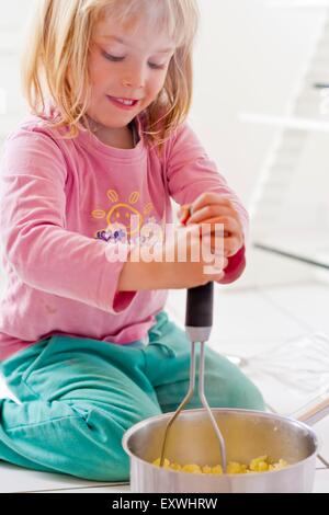 Mädchen, die Kartoffeln Stampfen Stockfoto