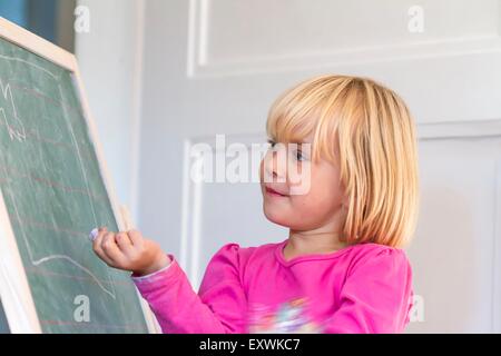 Mädchen spielen Schule an der Tafel Stockfoto