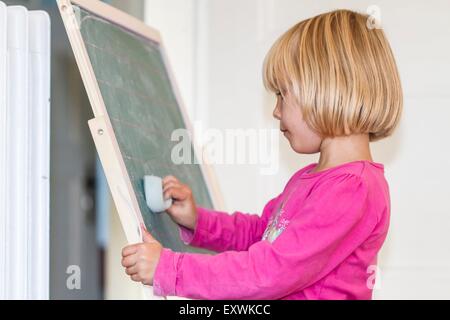 Mädchen spielen Schule an der Tafel Stockfoto