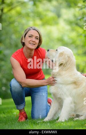 Reife Frau mit einem golden Retriever im Garten Stockfoto