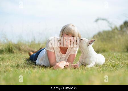 Frau auf der Wiese liegend mit eine sieben Monate alte französische Bulldogge Stockfoto