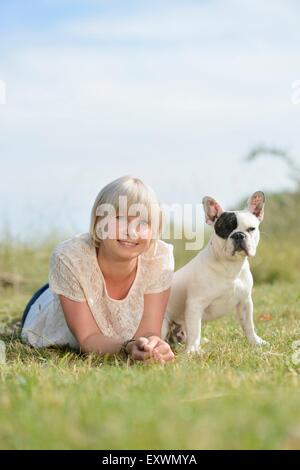 Frau auf der Wiese liegend mit eine sieben Monate alte französische Bulldogge Stockfoto