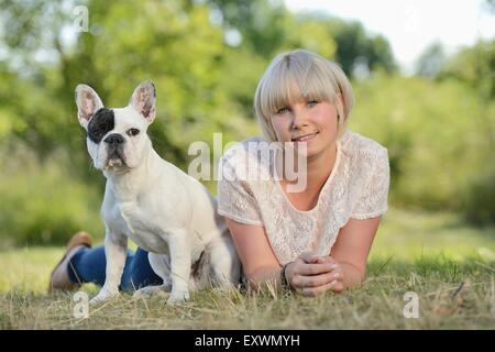 Frau auf der Wiese liegend mit eine sieben Monate alte französische Bulldogge Stockfoto