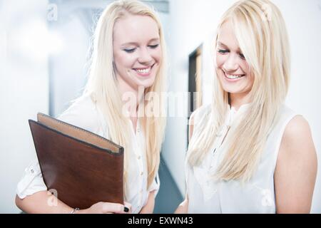 Zwei lächelnde blonde junge Frauen im Büro Stockfoto