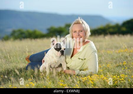 Frau auf der Wiese liegend mit eine sieben Monate alte französische Bulldogge Stockfoto