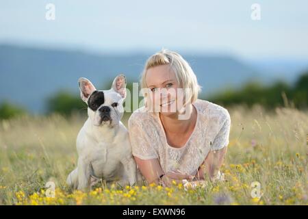 Frau auf der Wiese liegend mit eine sieben Monate alte französische Bulldogge Stockfoto