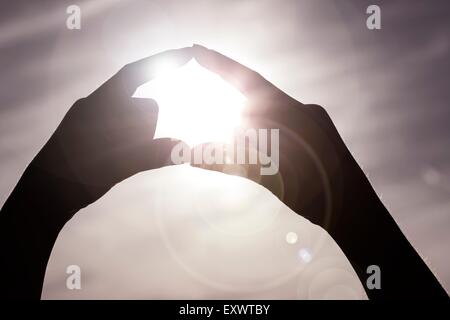 Fingern bilden Kreis um Sonne Stockfoto