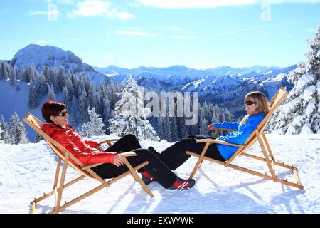 Zwei Frauen in liege im Schnee, Tegelberg, Ammergauer Alpen, Allgäu, Bayern, Deutschland, Europa Stockfoto