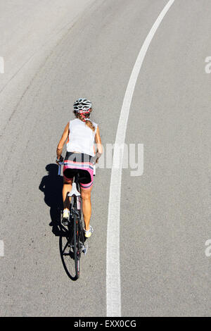 Radfahrer-Frau mit dem Fahrrad auf einer Landstraße Stockfoto