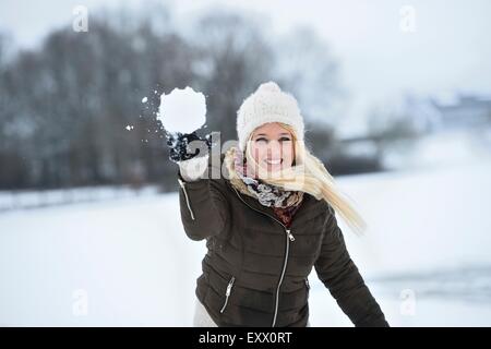 Glückliche junge Frau einen Schneeball werfen Stockfoto