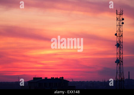 Turm von Mobilfunkantennen auf einem Hintergrund von roten Wolken bei Sonnenuntergang Stockfoto