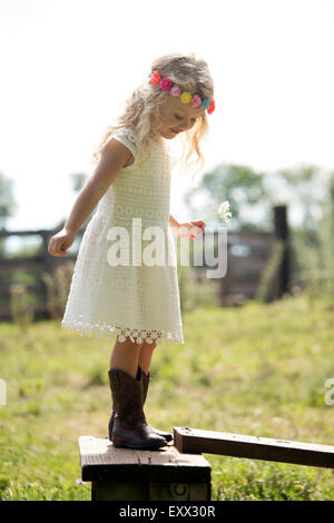Süße Mädchen im weißen Kleid stehen am Zaun auf Wiese (4-5) Stockfoto