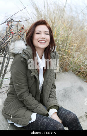 Porträt der Frau im Parka am Winter-Strand Stockfoto