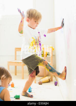 Jungen (2-3) Malerei auf Wand mit Händen und Beinen Stockfoto