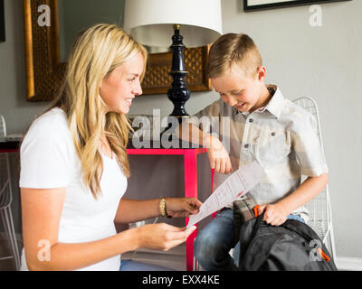 Lächelnde junge (6-7) zeigt Schoolpaper Mutter Stockfoto