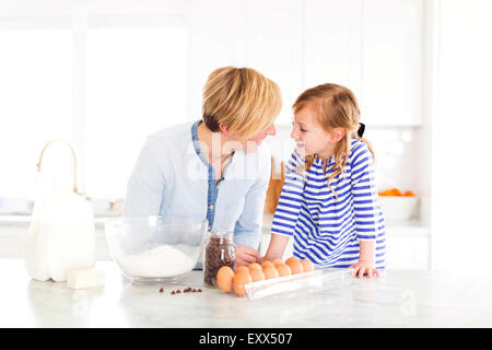 Mädchen (4-5) im Gespräch mit Mutter in der Küche Stockfoto