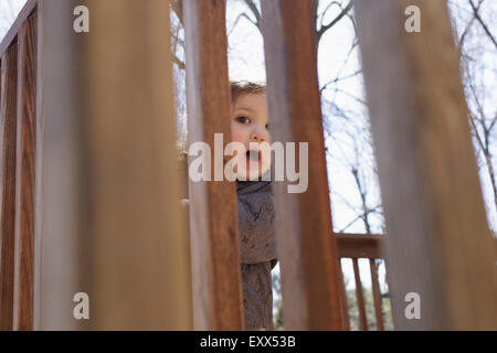 Porträt eines Mädchens versteckt sich hinter Zaun Stockfoto