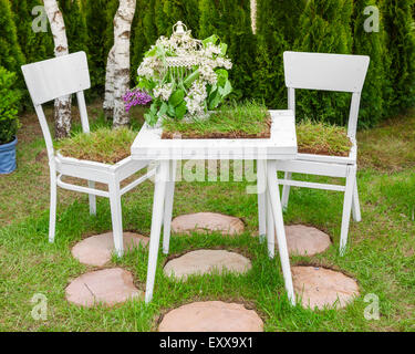 Garten Zusammensetzung - Tisch und Stühle bedeckt grünen Rasen, Vogelkäfig mit Flieder im Urlaub in Krankenschwester Stockfoto